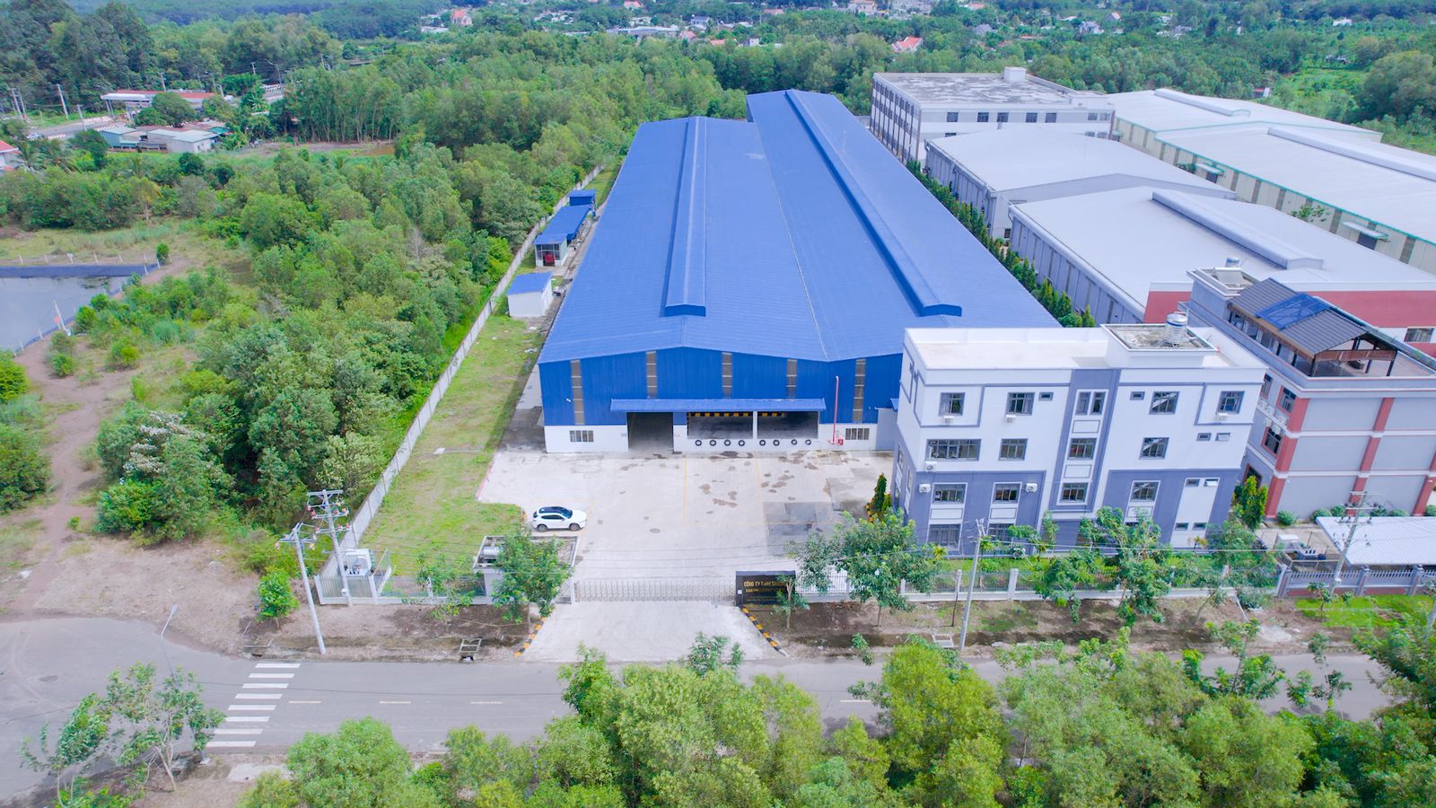 Aerial view of the SANLIAN factory: two blue-roofed workshops and a four-storey office block
